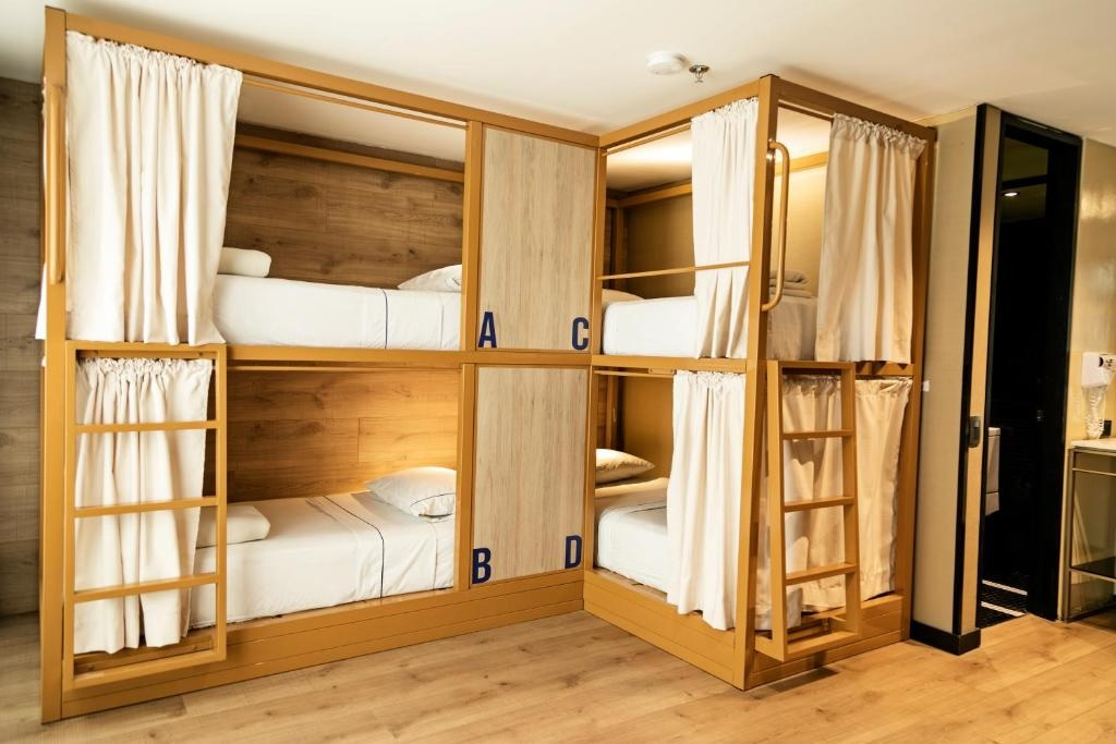 A room with bunk beds, each with a curtain, in a wooden structure.