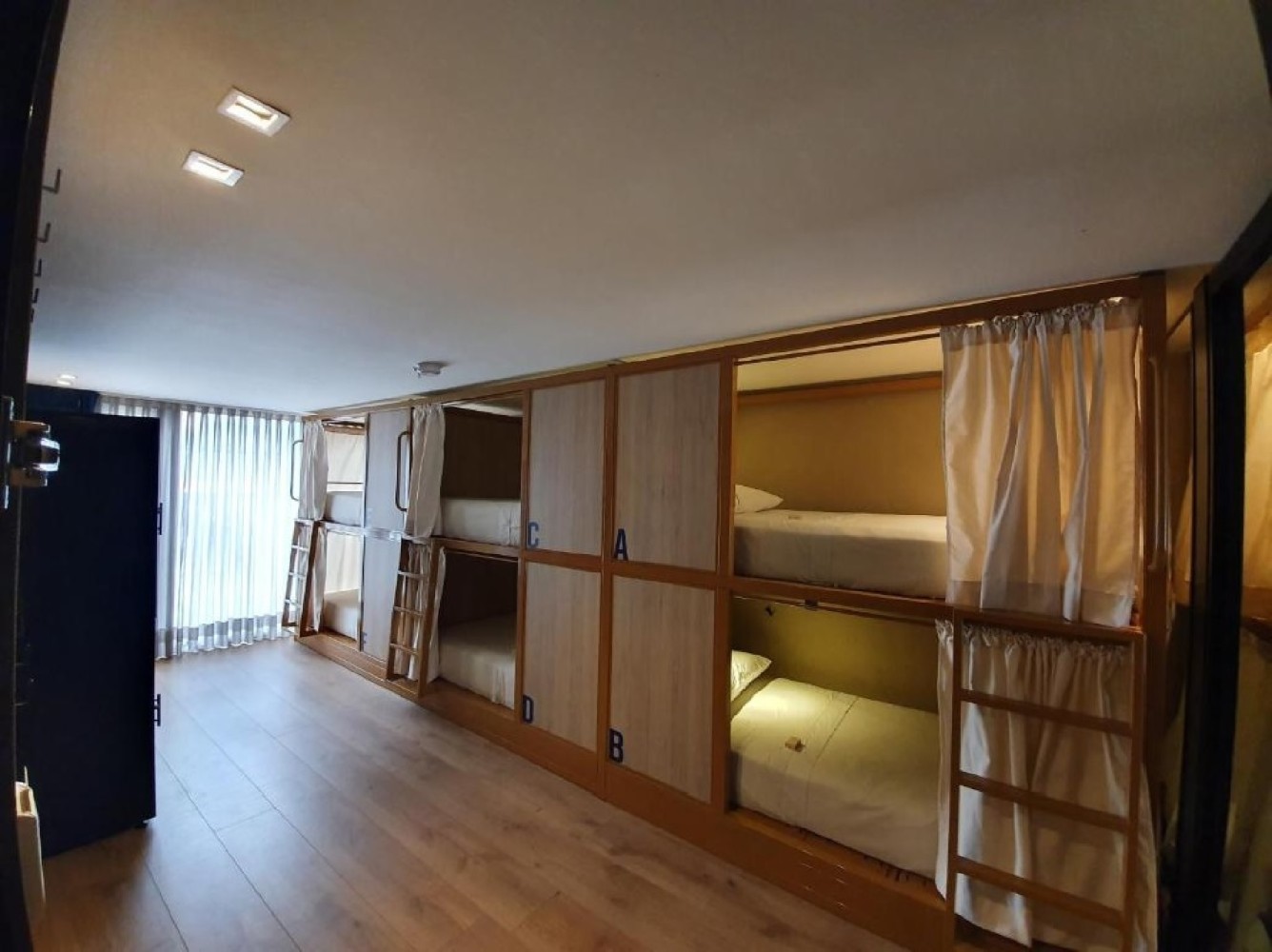 A wide view of a dorm room with bunk beds and wood paneling
