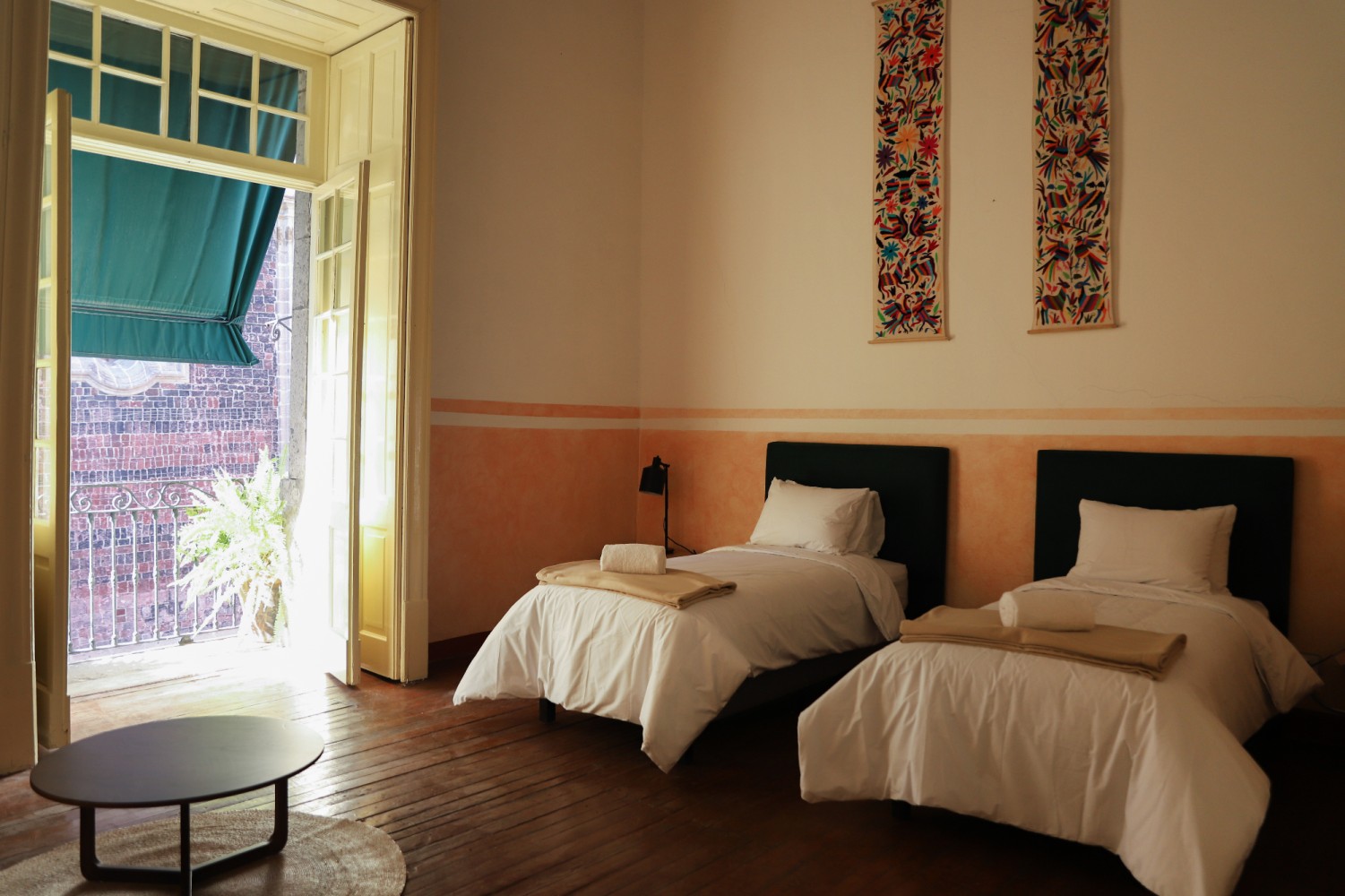 A room with two beds, a doorway, and artwork on the wall.