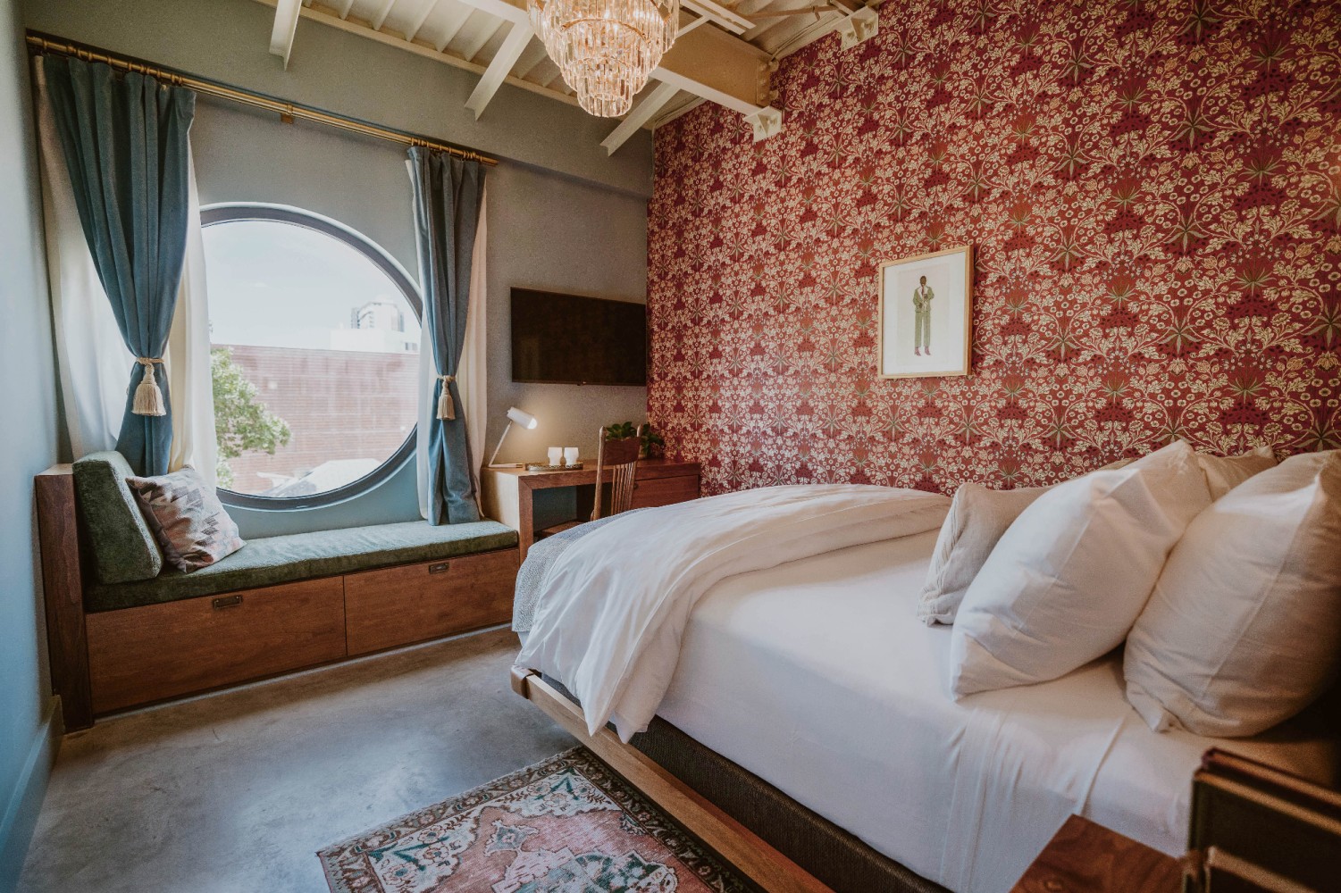 A hotel room with a large bed, a window bench, and a chandelier