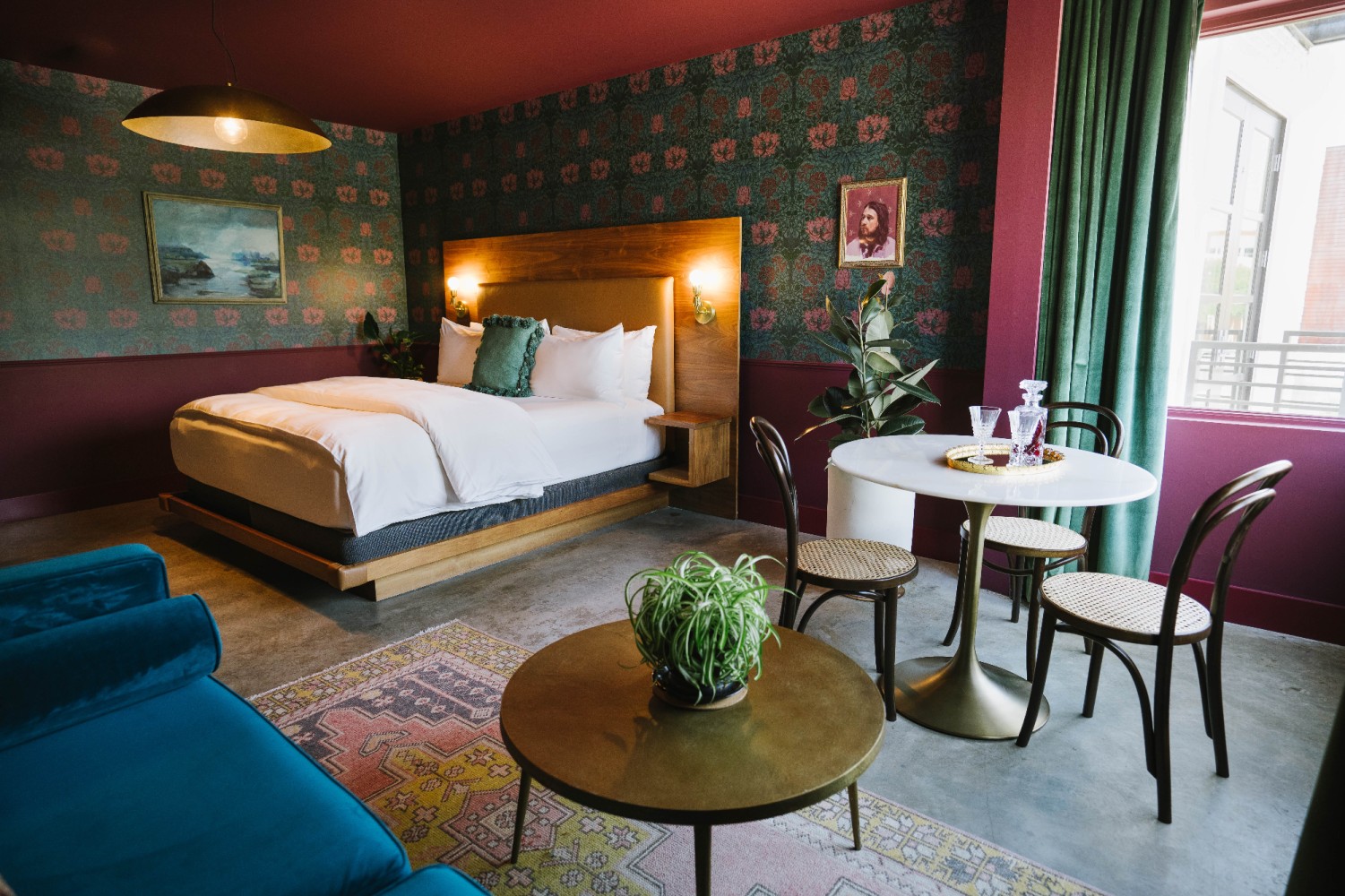 A wide view of a hotel room with a bed, sofa, table, and chairs.