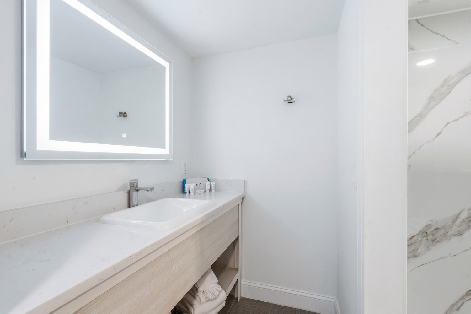 A modern bathroom with a large mirror, sink, and shower.