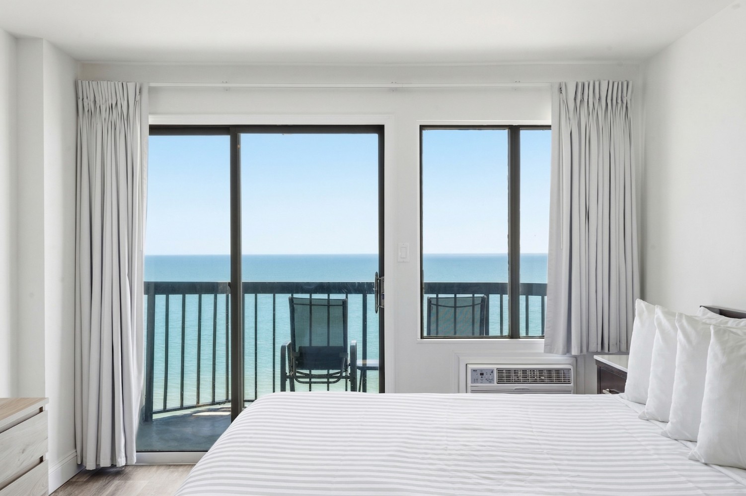 A hotel room with a bed, balcony, and ocean view