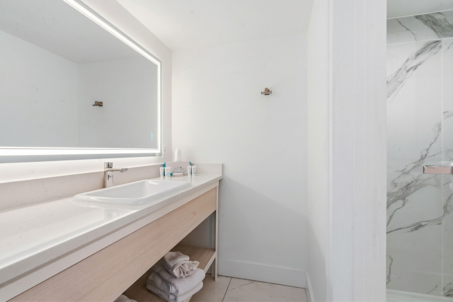 a clean bathroom with a large mirror, sink, and shower