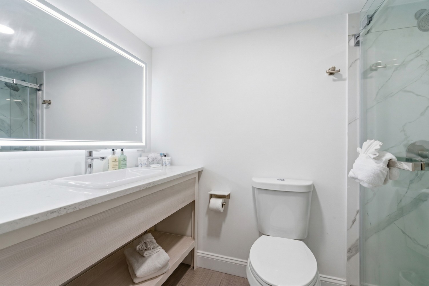 A clean bathroom with a sink, toilet, and shower.