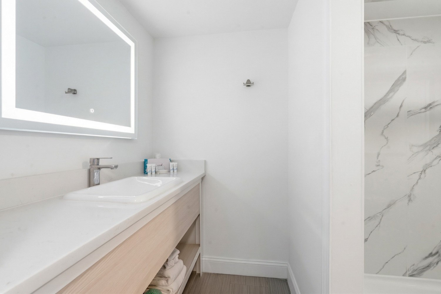 a clean bathroom with a large mirror, a double vanity sink, and a tiled shower