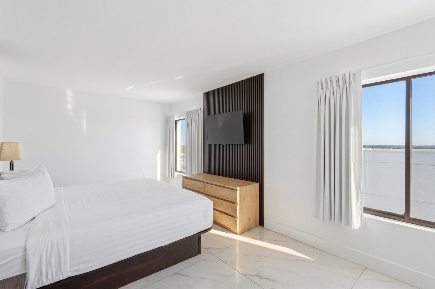 A bright and clean hotel room with a large bed, dresser, and TV.