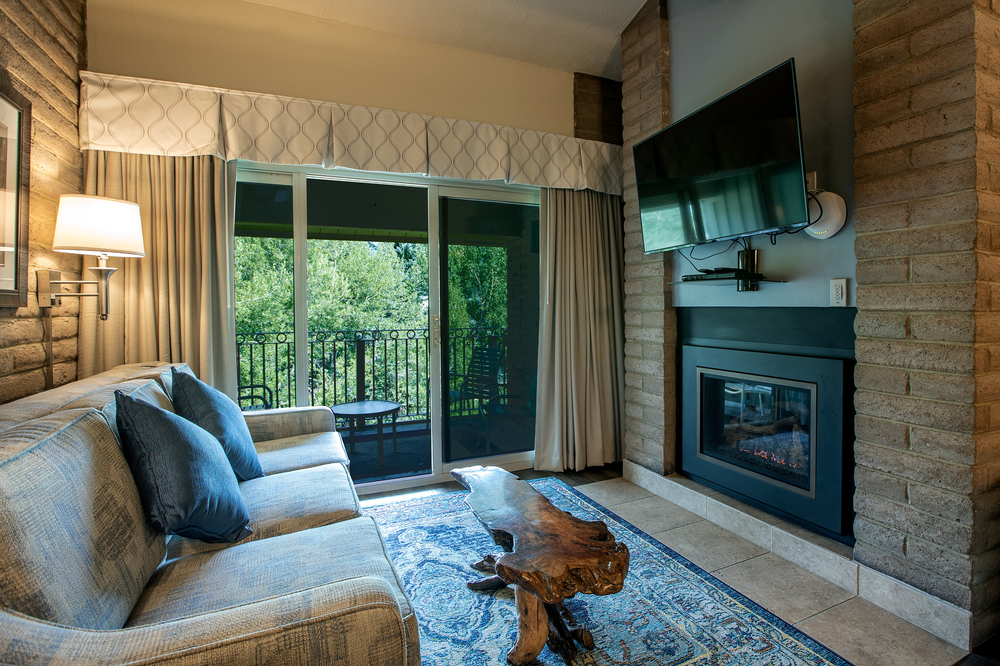 A living room with a sofa, fireplace, TV, and balcony