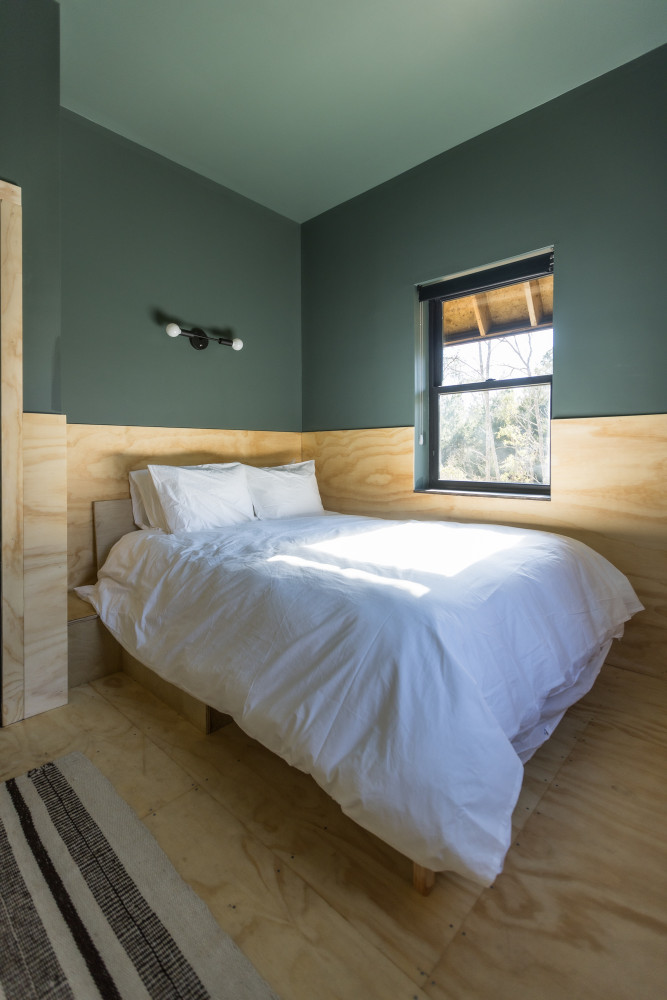 A bedroom with a bed, window, wooden floor, and wooden headboard