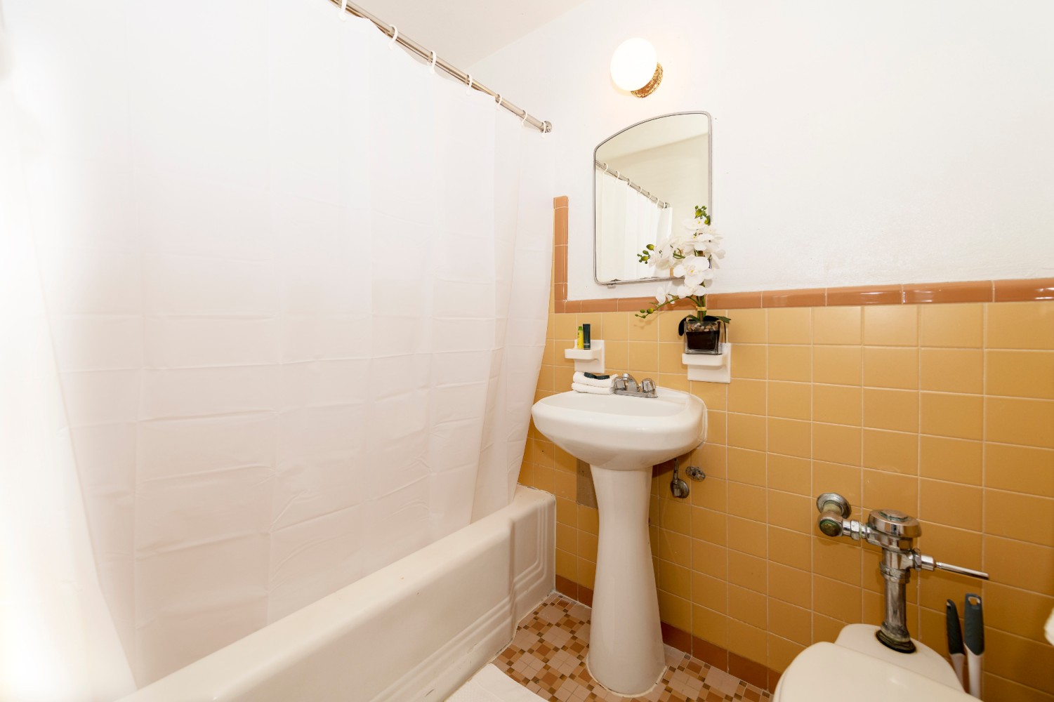 A bathroom with a pedestal sink, bathtub, toilet, and yellow tiles