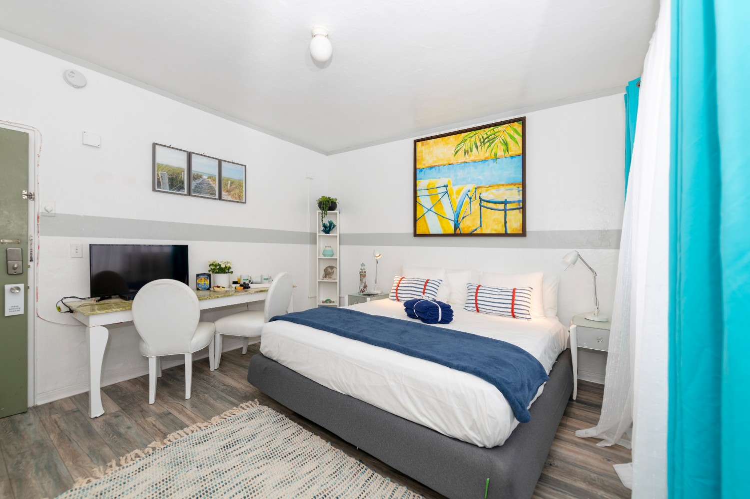 A hotel room with a bed, desk, TV, and chair.