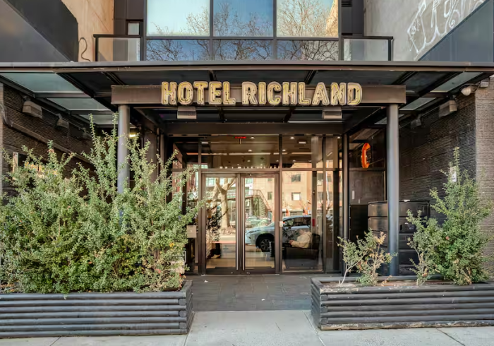 The entrance of Hotel Richland with a sign above the door and planters on either side.