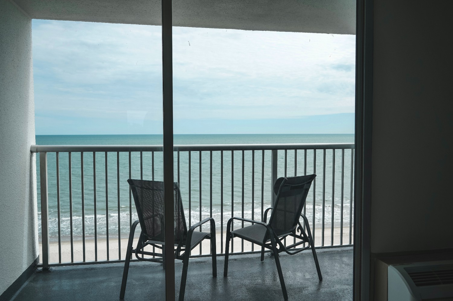 A balcony with two chairs and an ocean view