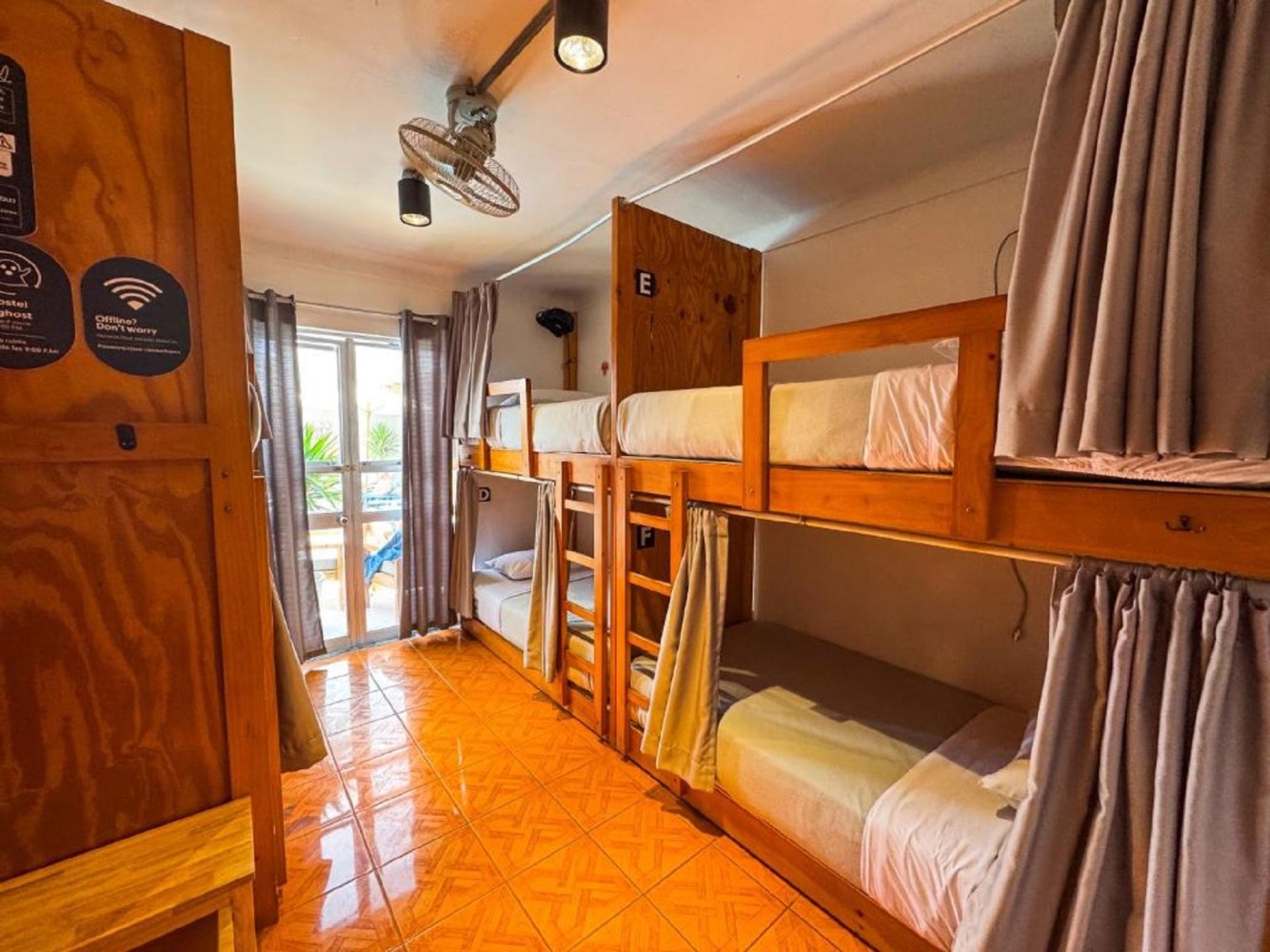 A room with bunk beds, orange tiles, and a ceiling fan.